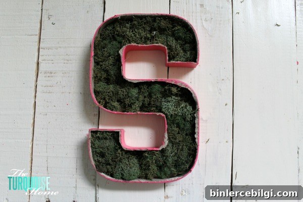 Cut the top off of a simple paper mache initial from Hobby Lobby and fill it with moss and flowers for a sweet addition to a baby girl's nursery. | DIY Flower and Moss Initial Art via TheTurquoiseHome.com