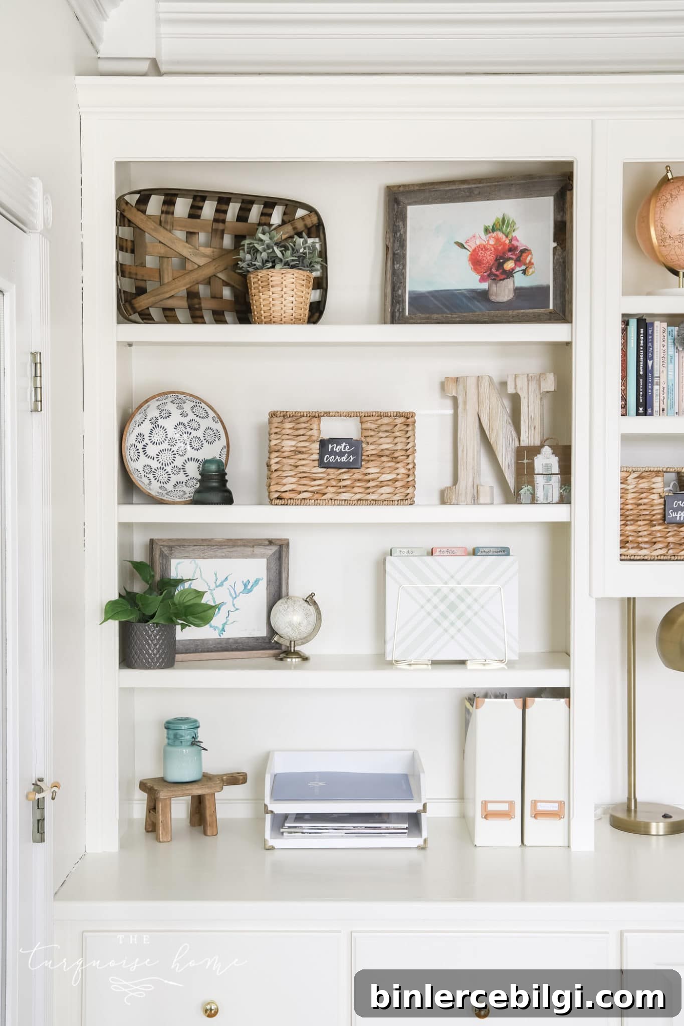 white bookshelves with greenery, books, boxes and art.