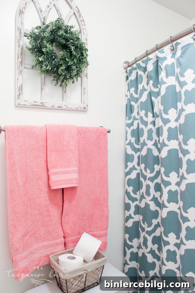 Window arch above the toilet in the girls' bathroom refresh | Use a basket for toilet paper storage and a over-the-toilet cabinet if needed | bathroom makeover | pink towels | antique distressed window frame | eucalyptus wreath