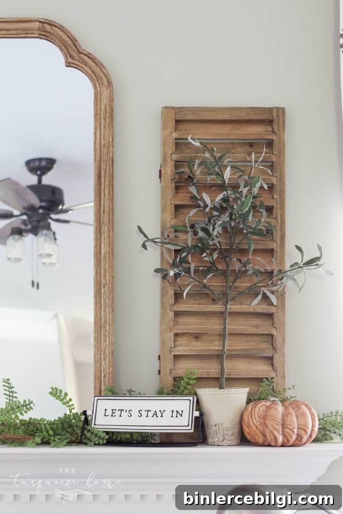 Shutter and olive tree with 'let's stay home' sign and a wood grain pumpkin.