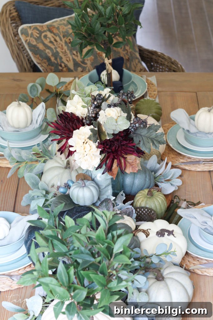 Pumpkins and Greenery Fall Tablescape with bay leaves in a pot and fall floral arrangement.