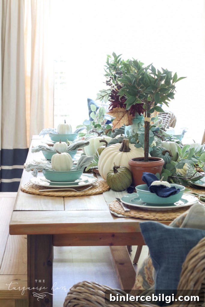 Pumpkins and Greenery Fall Tablescape with bay leaves in a pot and fall floral arrangement.
