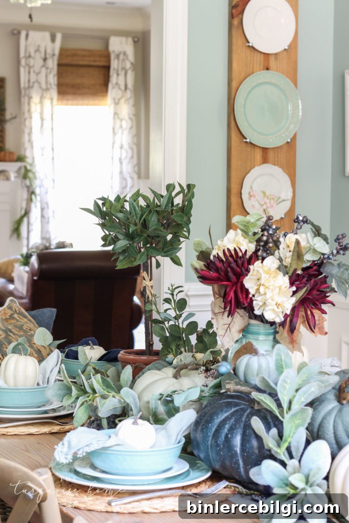 Pumpkins and Greenery Fall Tablescape with bay leaves in a pot and fall floral arrangement.