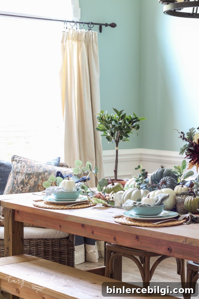 Pumpkins and Greenery Fall Tablescape with bay leaves in a pot and fall floral arrangement.