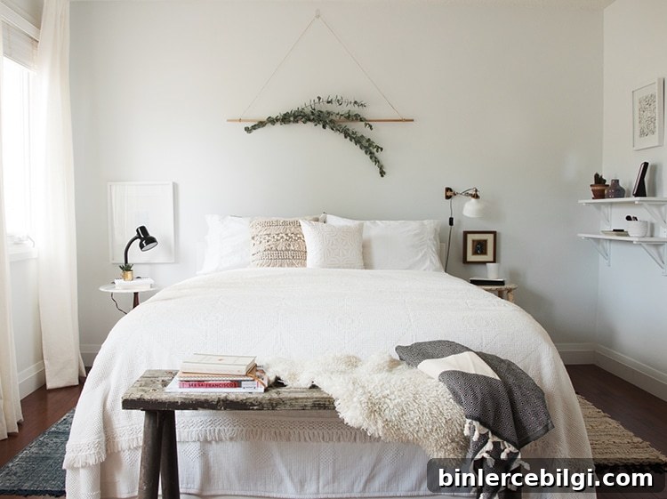 sprigs of eucalyptus hang on the wall above a bed