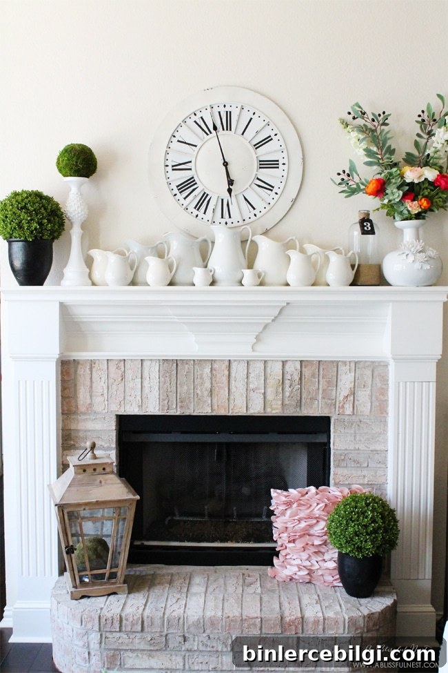 spring mantel decor that includes greenery, blooms and pitchers of various sizes