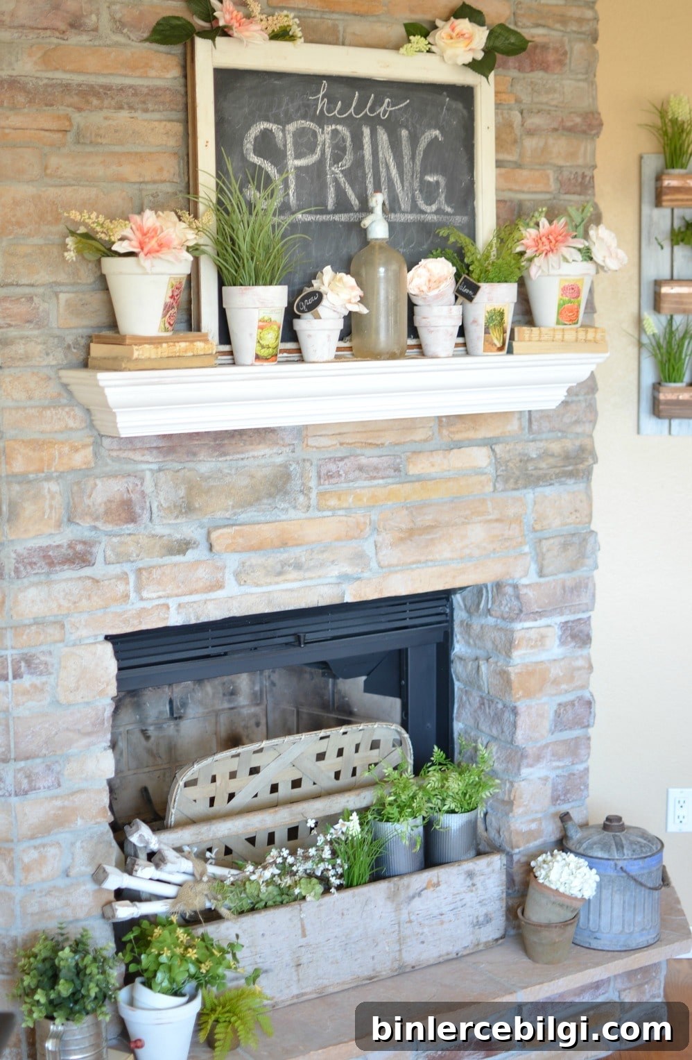 fireplace mantel with spring decor including potted blooms and a sign
