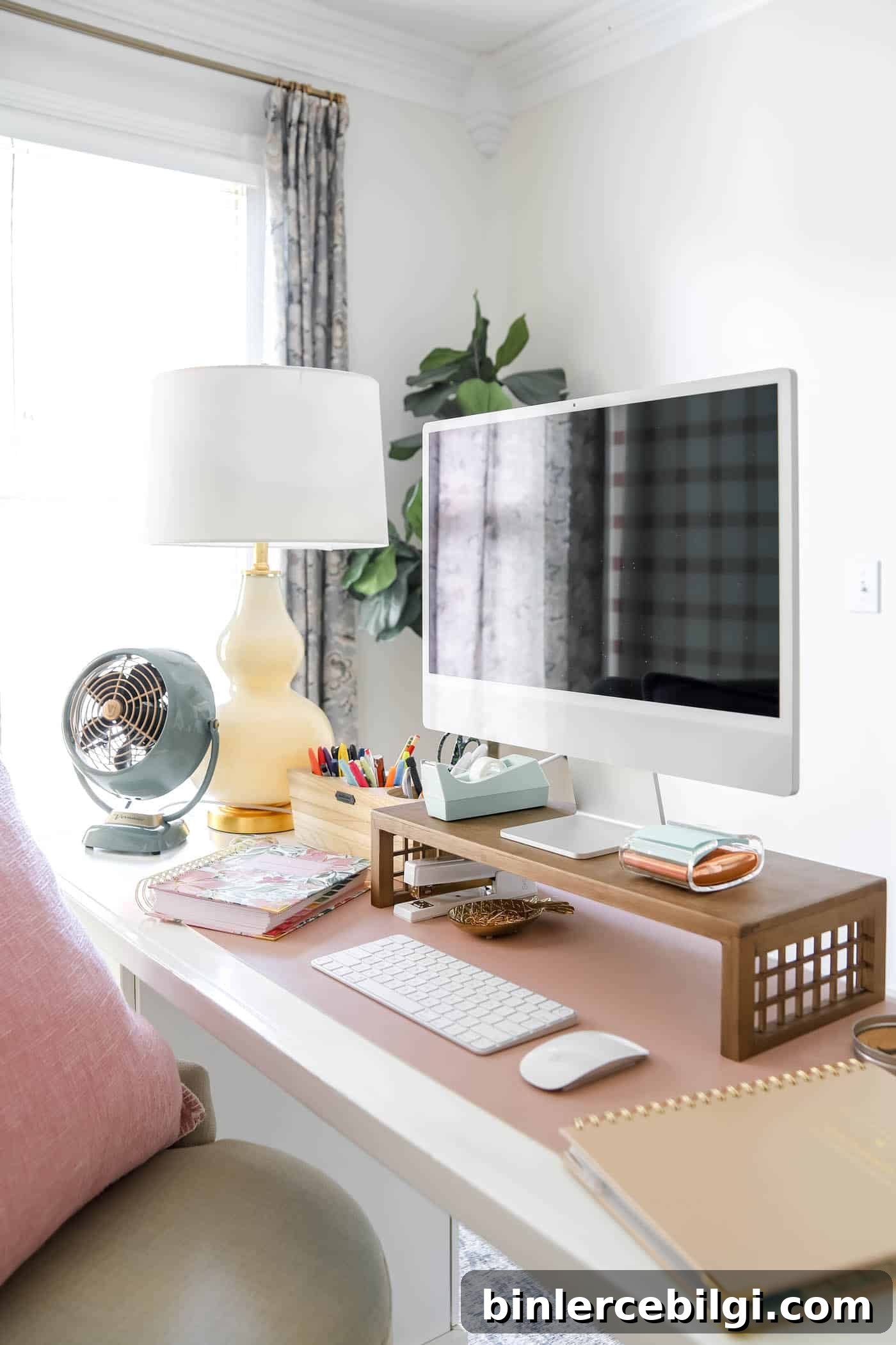 organized desk space with mc computer and desk riser, fan and lamp.