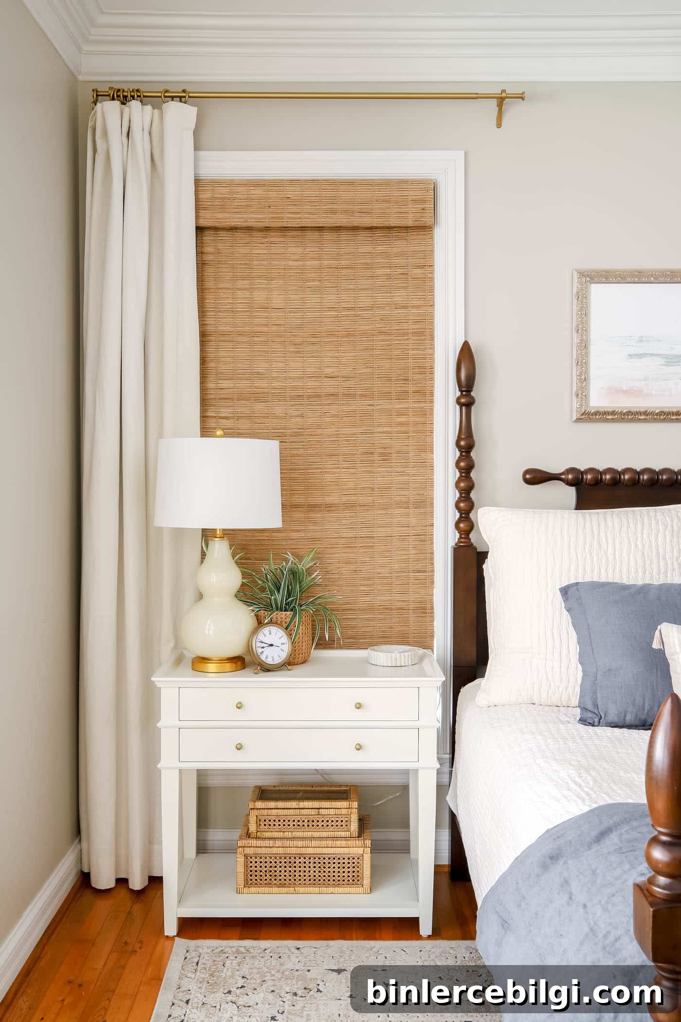 nightstand with lamp, clock and decorative boxes with ivory curtains, bamboo shades and revere pewter was in bedroom.