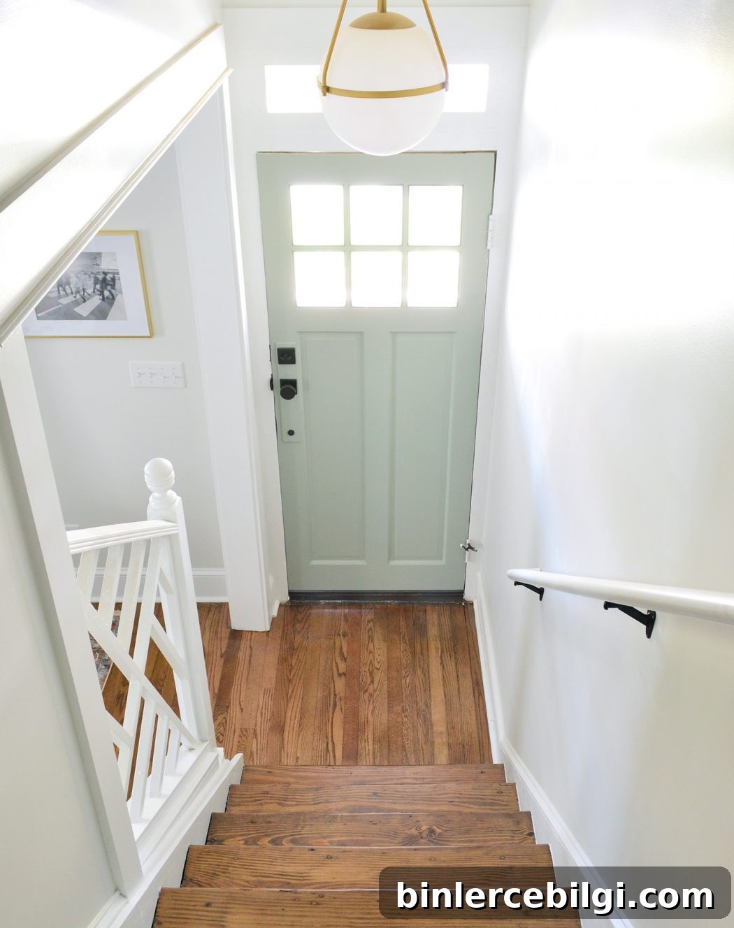 Sherwin Williams Oyster Bay Review: Blue-Green Paint Shade 8 Light-filled entry way with wooden floor and front door painted Oyster Bay
