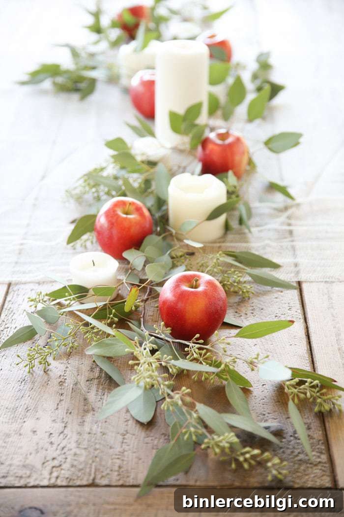 table centerpiece with apple, greenery, and candles.