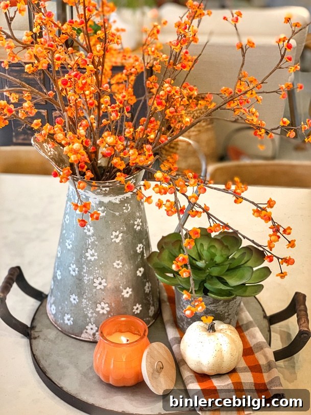 Fall flower arrangement with bittersweet branches, succulent, pumpkin, candle