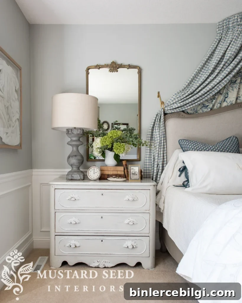 Primary bedroom with gray walls, fabric valance over the bed, antique painted dresser and an antique mirror.