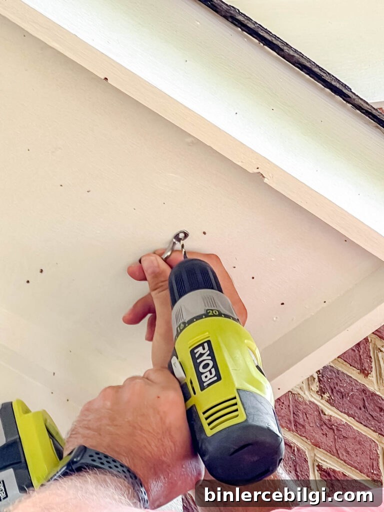 installing string lights with a hook on a side of a house.