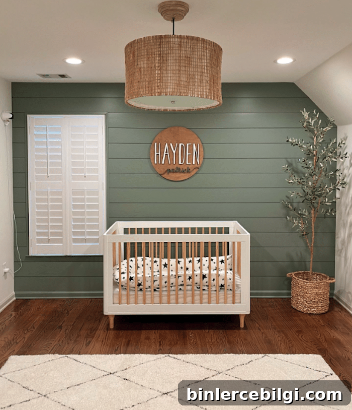 Boy's nursery with green shiplap walls and a modern white and wood crib.
