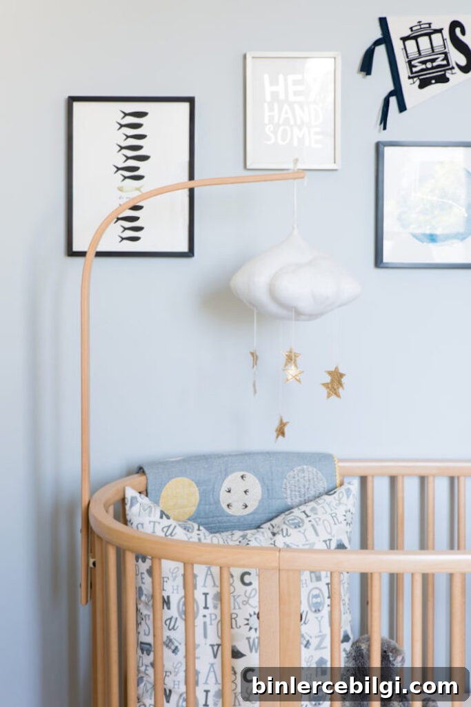 Blue walls in a boy's nursery with cloud hanging mobile and wall art.