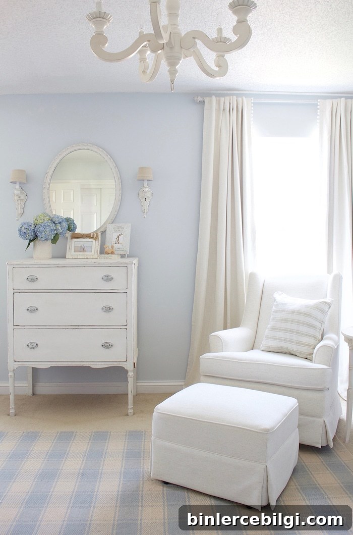 Traditional boy's nursery with blue walls and white glider and ottoman.