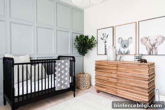 Wall moulding in nursery painted Boothbay Gray and animal photos on opposite wall with a black crib.