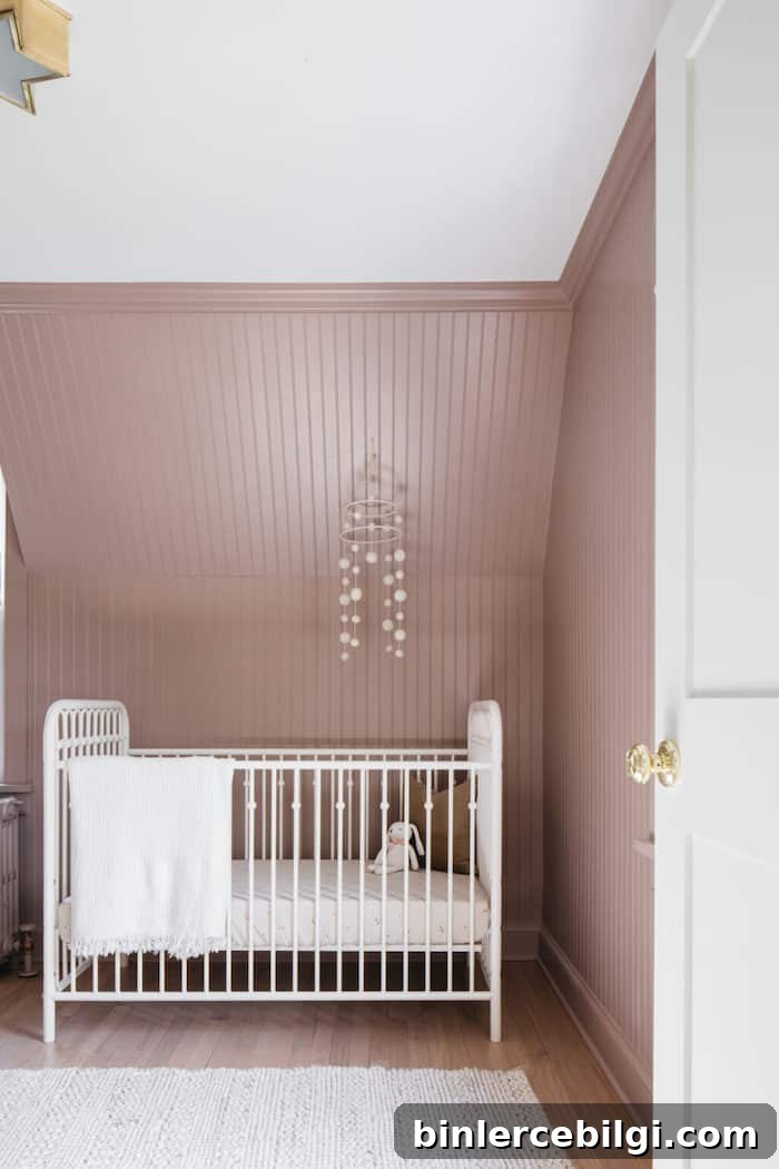 Seaside Sand (pink) walls with beadboard and a white crib with a mobile hanging over it.