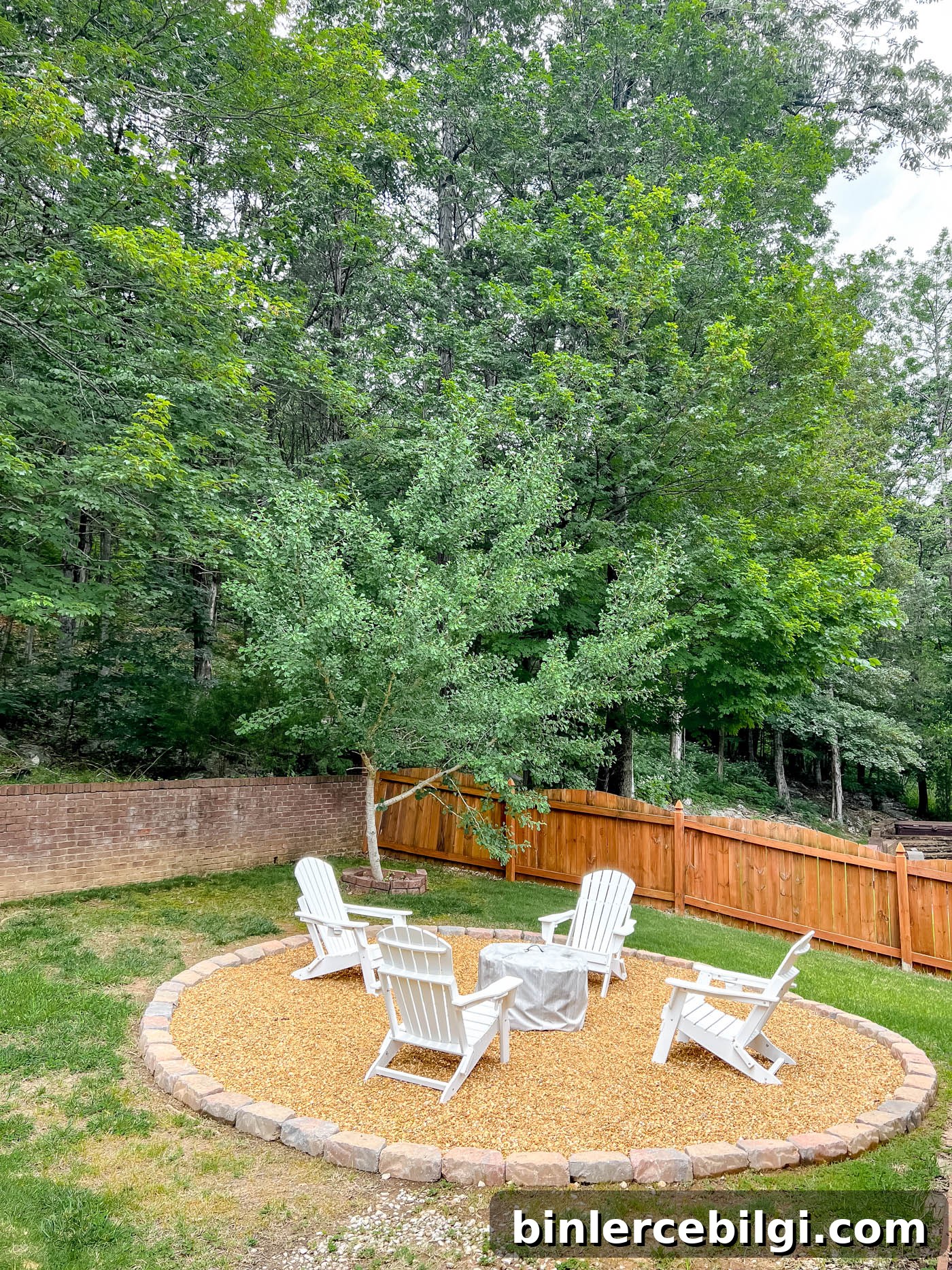 pea gravel fire pit in the backyard with white adirondack chairs and solo stove fire pit.