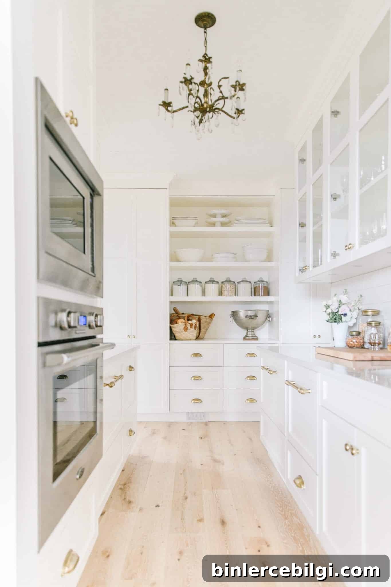 A white scullery with open shelving and two counters for tasks.