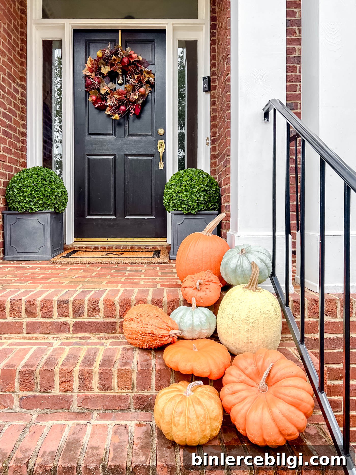 faux pumpkins on a front porch with autumn wreath.