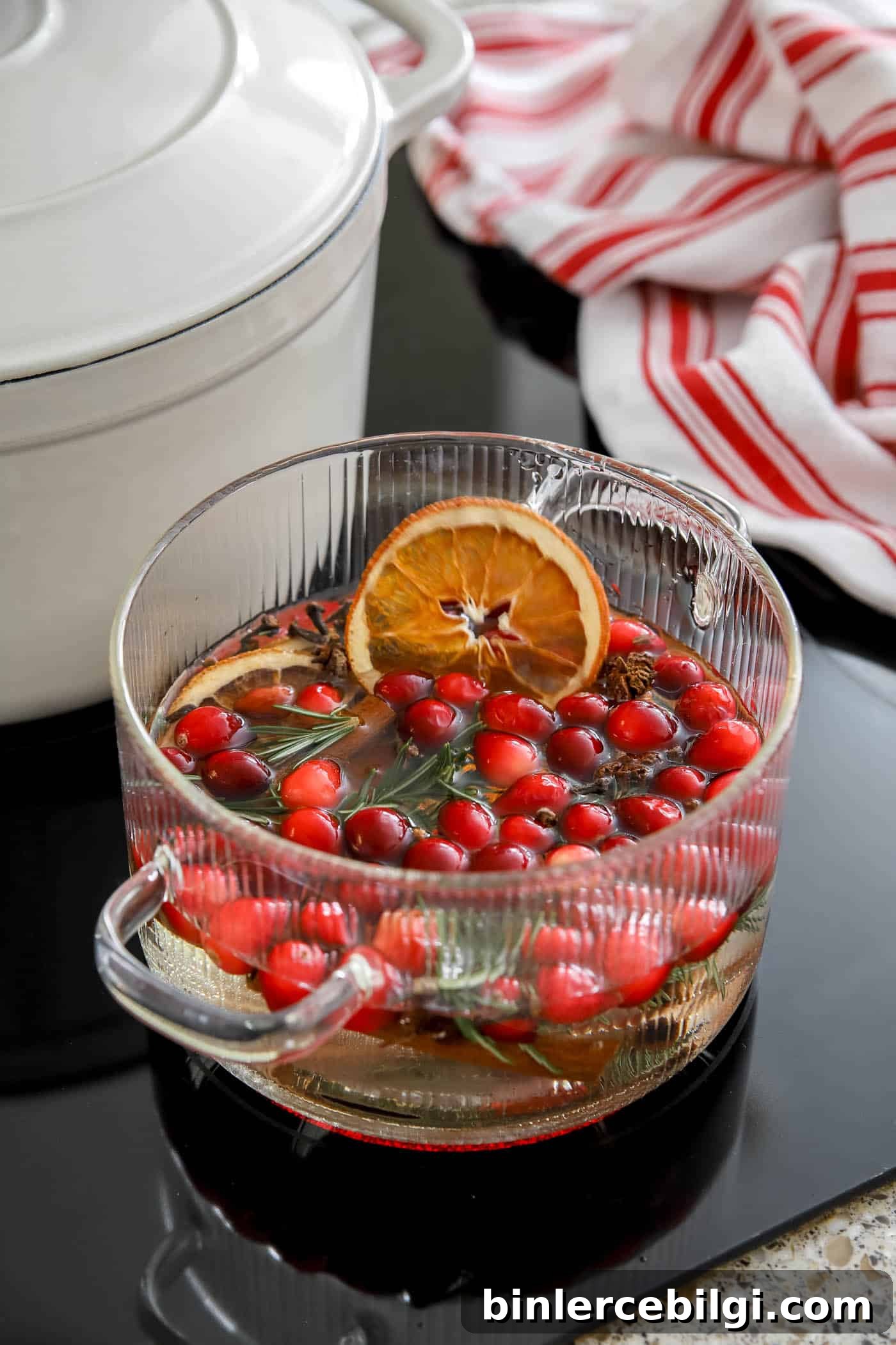 DIY Christmas Simmer Pot Recipe with Free Printable Gift Tags 6 clear pot with Christmas simmering ingredients inside it on the stovetop.