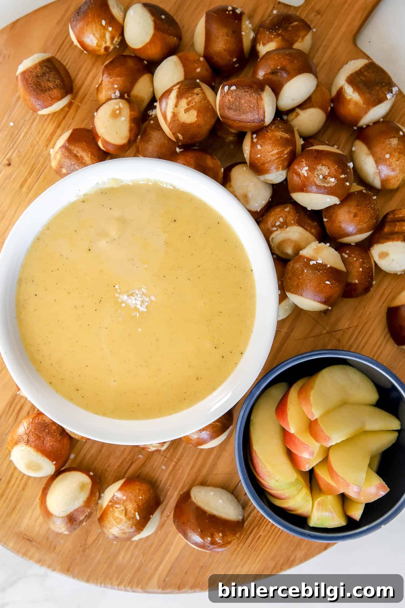 Beer cheese pretzel dip on a charcuterie board with pretzel balls and apple slices