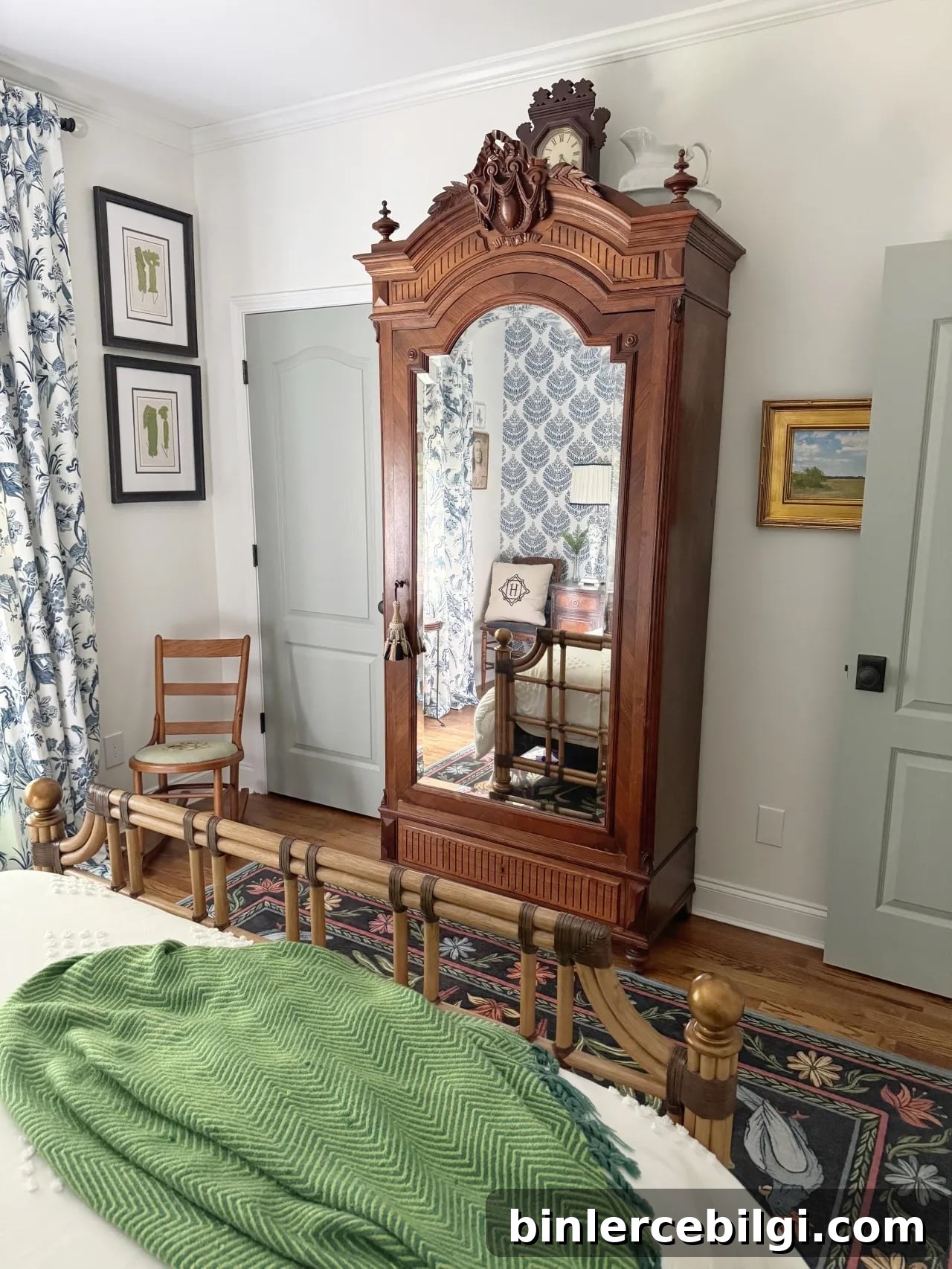 chinoiserie style brown armoire in a bedroom with light colored walls.