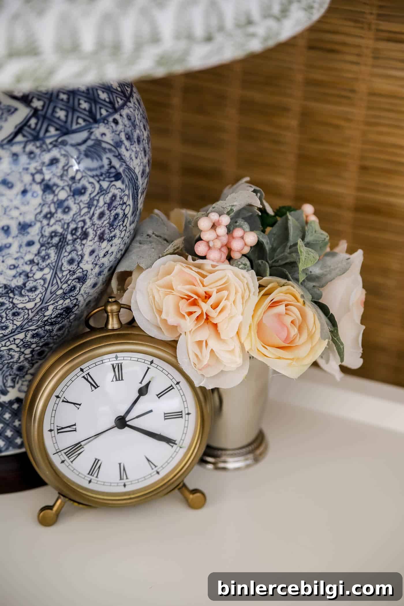 small bouquet of faux flowers in a mint julep cup on a nightstand