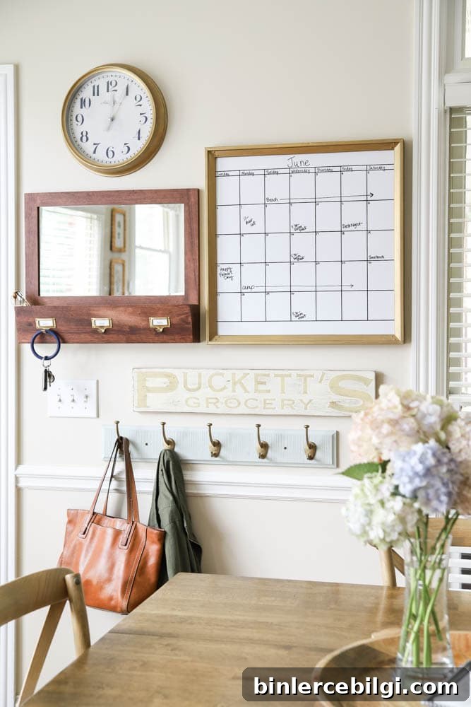 calendar, mirror, mail sorter and hooks in the entry way of a kitchen area.