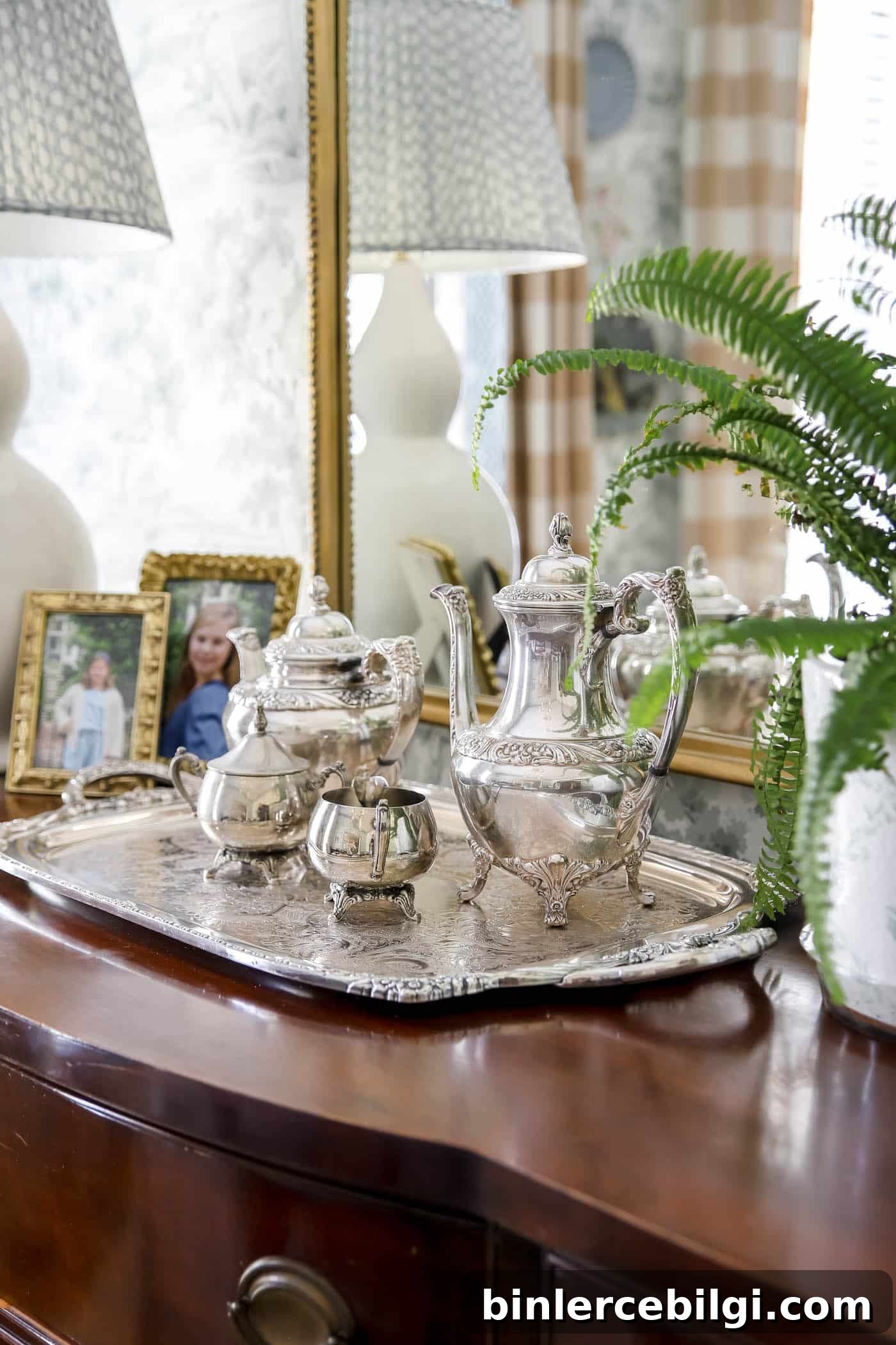 silver tea tray, coffee pot, tea pot and cream and sugar pots on a wood dining buffet. 
